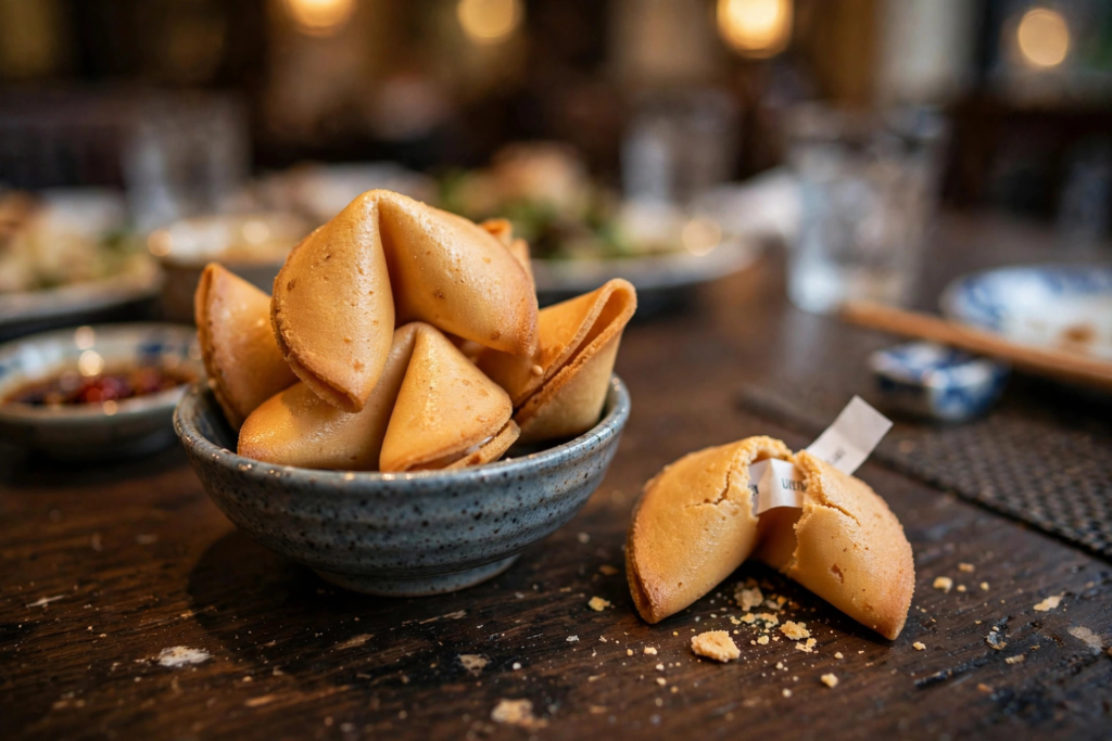 A bowl of golden fortune cookies on a Chinese restaurant table, one cracked open